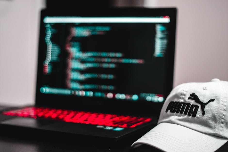 The image displays a close-up view of a computer screen with a code editor open, showing lines of colorful programming code on a dark background. The code includes syntax in various colors such as gre